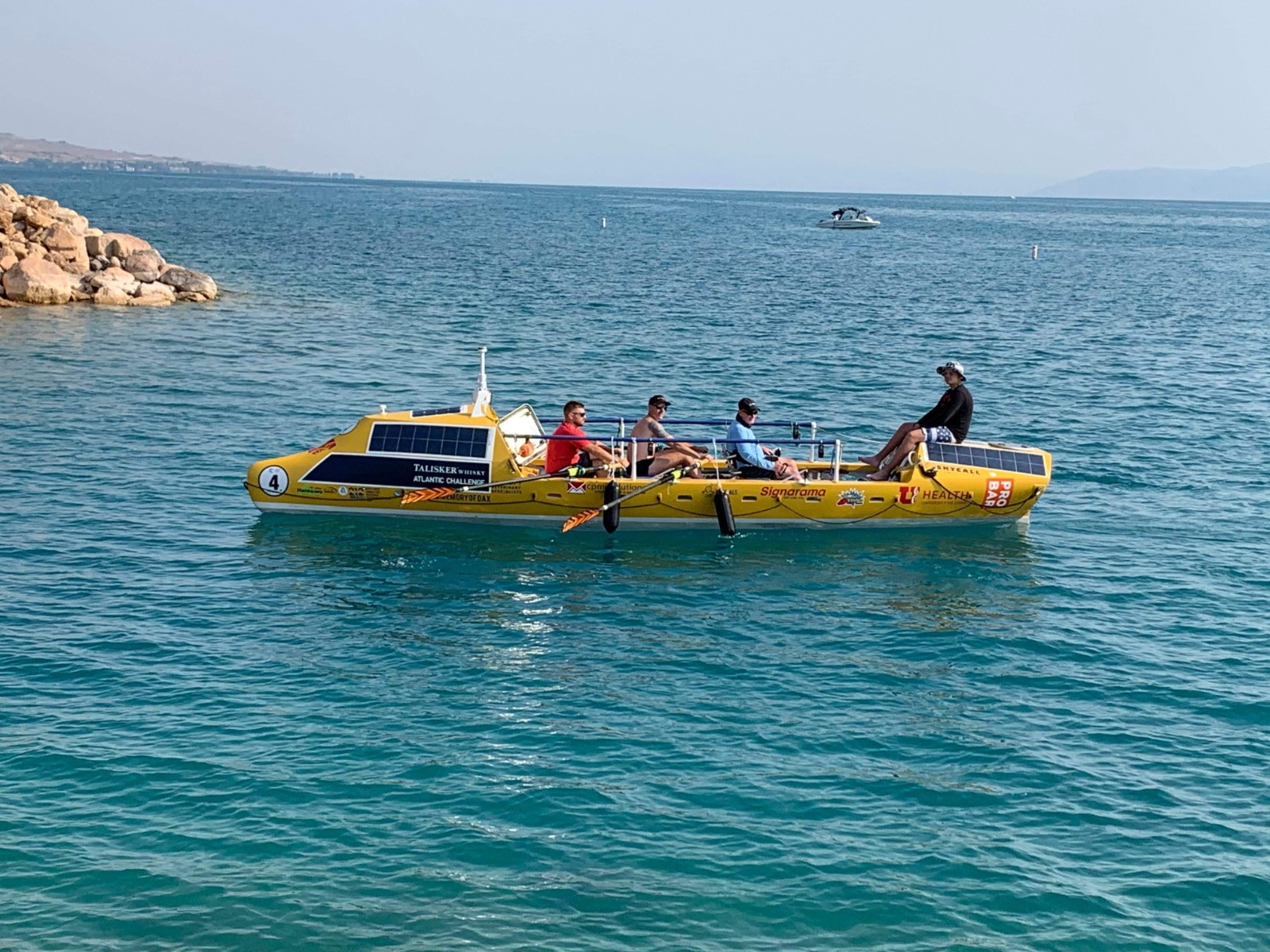 Ocean rowers aboard a yellow boat on blue water